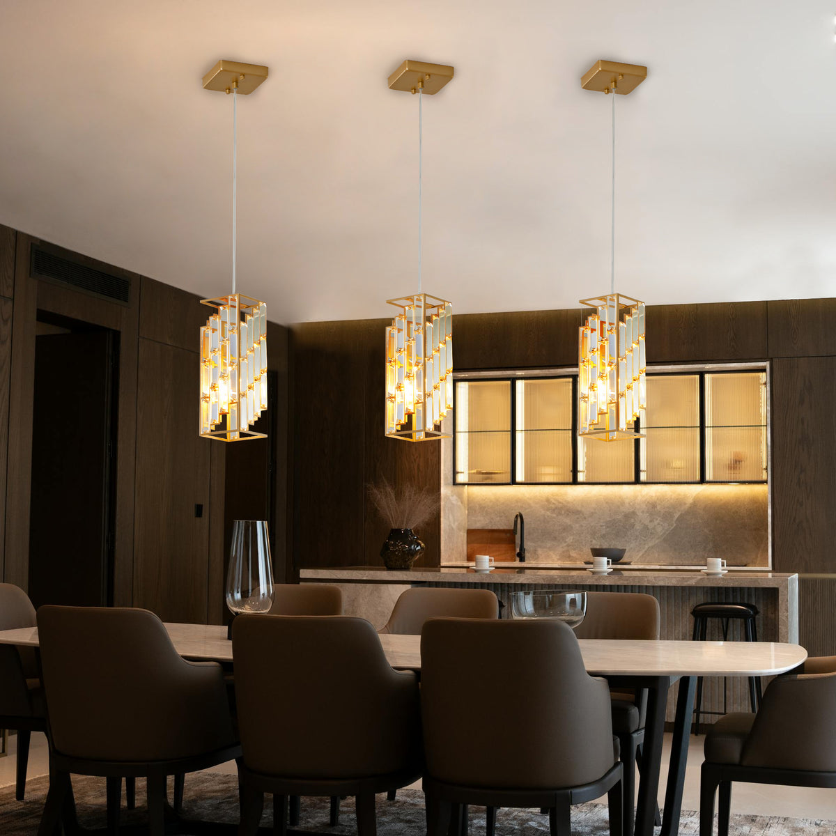 An elite crystal prism design pendant trio casting a glamorous, multi-faceted warm light across an upscale room.
