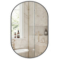 Aura matte black oval wall mirror mounted vertically in a minimalist modern bathroom